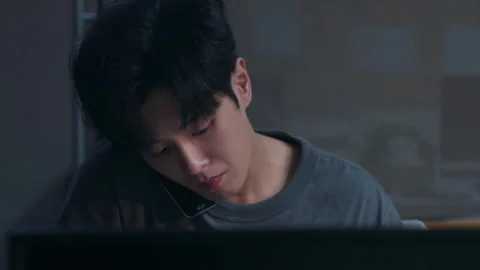Stressed asian man multitasking on phone while working late at night Stock Footage 333800787