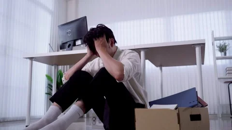 Stressed Asian man sits on office floor head in hands beside packed box aft.. Stock-Footage 345196319