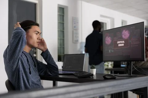 Stressed asian web developer having security breach alert on computer screen Foto stock