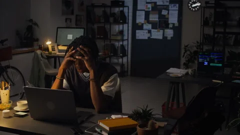 Stressed Black Man Experiencing Burnout Working Late on Laptop in Office Stock Footage 338416594