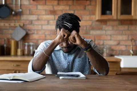 Stressed black man sit by copybooks smartphone overloaded by information Stock Photos