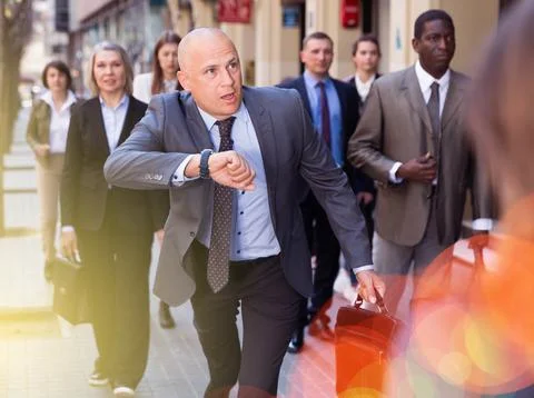 Stressed businessman checking time and running Stock Photos