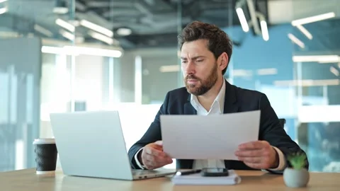 Stressed Businessman Confronts Complex Documents and Laptop Challenges Stock Footage 329091288