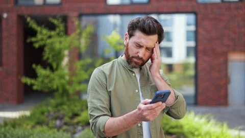 Stressed Businessman Having Headache While Using Phone Outdoors Near Office Stock Footage 308689349