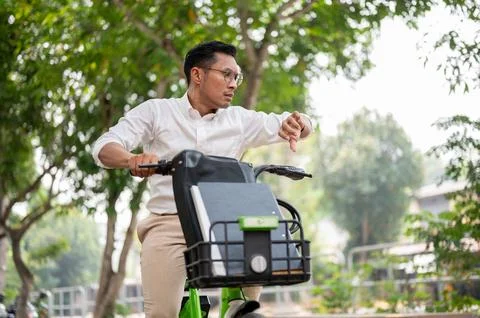 A stressed businessman is in a hurry to get to work, riding a bike, checkin.. Stock Photos
