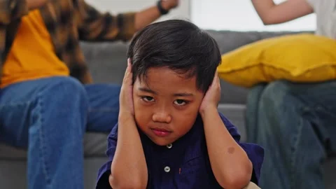 Stressed child blocking out noise while parents have heated discussion behind 库存影片 335178916
