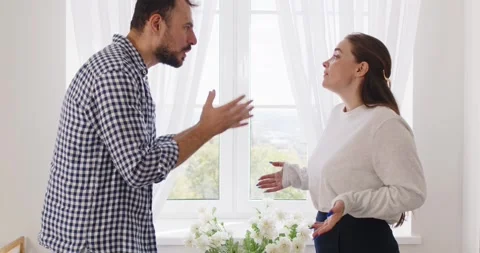 Stressed couple arguing at home by window during tense relationship conflict Stock Footage 330925136