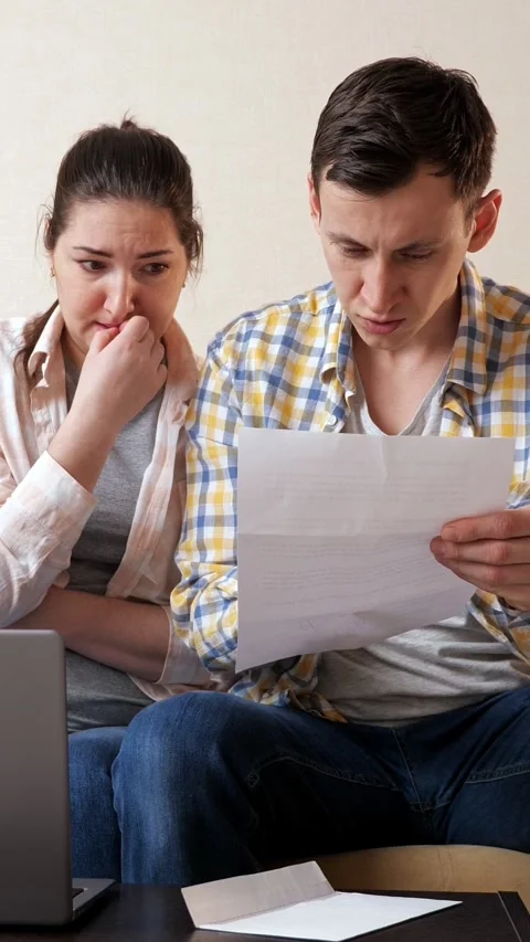 Stressed couple reading a shocking letter with bad news, young family facing Vidéo 342907316