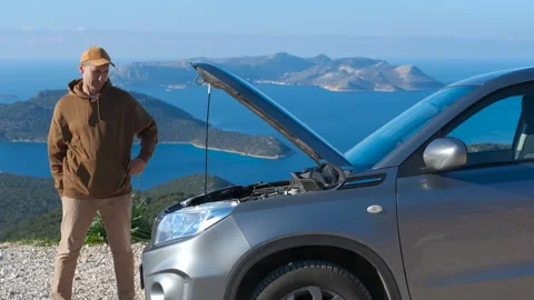 Stressed driver checking under the hood of a broken car. Stock Footage 332796960
