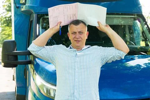 Stressed driver holding documents on head near truck Fotos Stock