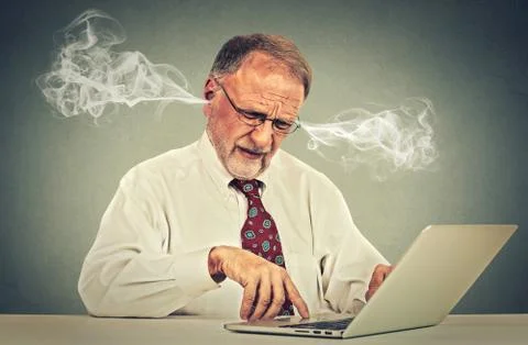 Stressed elderly old man using computer blowing steam from ears Stock Photos