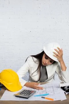 A Stressed Engineer Diligently Reviewing Complex Plans in a Busy Office Stock-Fotos