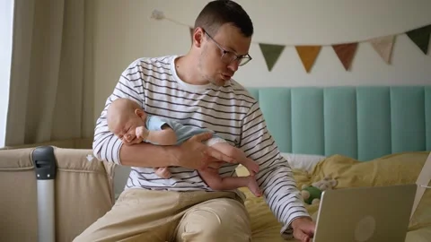 Stressed father multitasking while working from home, holding a crying newborn Video stock 344257513