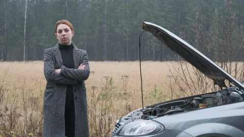 Stressed female driver standing by broken car Stock Footage 144063929