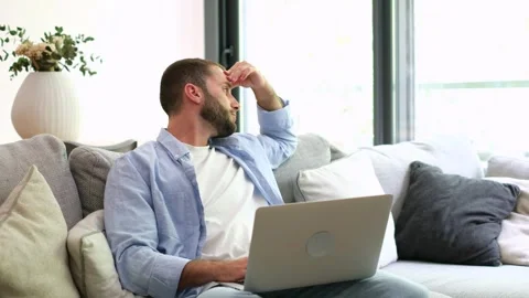 Stressed freelancer feeling tired while working on laptop at home Stock Footage 335588556