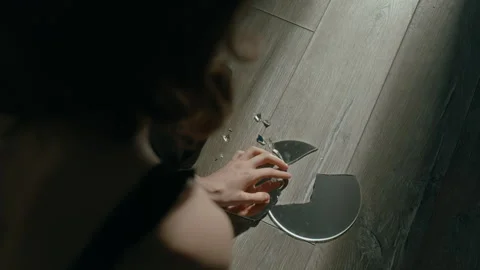 Stressed Girl Looking at Her Reflection in Shard of Broken Mirror on Floor 動画素材 301104257