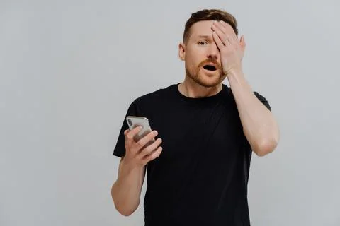 Stressed guy receiving message with bad news on smartphone, being in shock Stock Photos