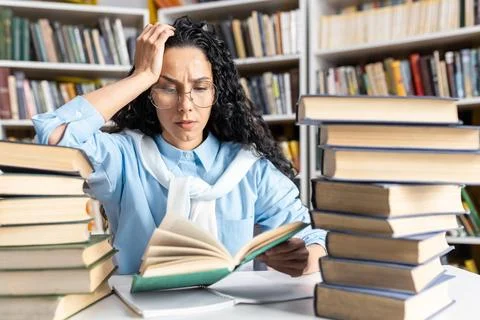 Stressed Hispanic student studying with many books around Stock Photos