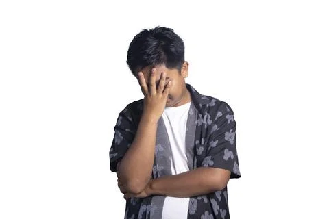 Stressed Indonesian man looking down while covering his face with one hand .. Stock Photos