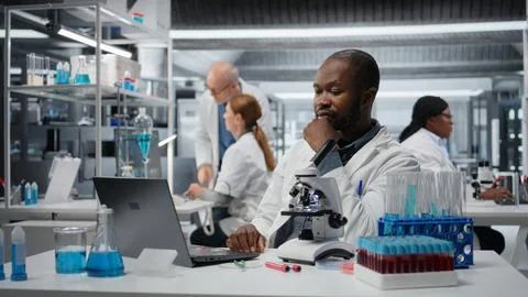 Stressed lab chemist feeling overwhelmed while working on laptop Stock Photos