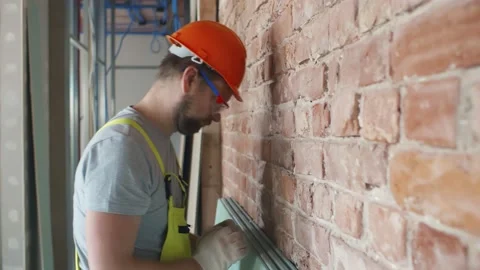 Stressed male builder in protective hardhat heating head against wall Stock Footage 133636675