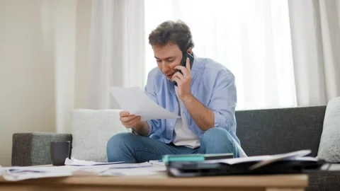 Stressed man arguing on phone over unpaid utility bills and rising energy prices Stock Footage 343752697