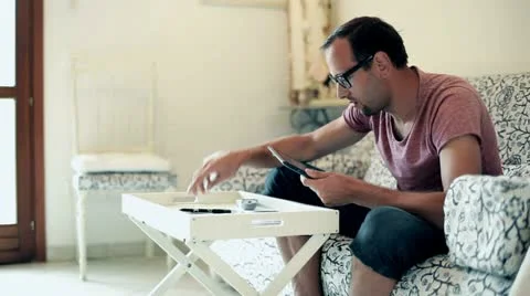 Stressed man doing his finances with tablet computer at home Stock Footage 12622871