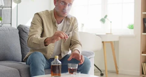 Stressed man drinking whiskey at home, concept of alcohol addiction and Stock Footage 335772369
