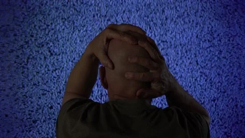 A stressed man in front of a TV set with noise and static Stock Footage 234347528