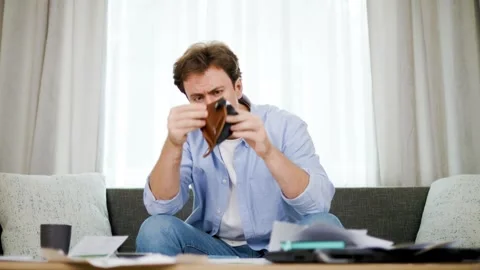 Stressed man holding empty wallet while looking at utility bill papers. High ene Stock Footage 341675583