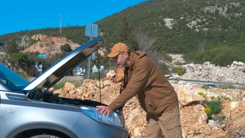 Stressed man looking at broken car engine on roadside. Stock Footage 330686306