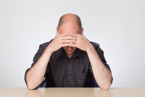 Stressed man looking down at desk Stock Photos