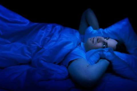 Stressed man lying awake in bed at night suffering from insomnia. Experienc.. Stock-Fotos