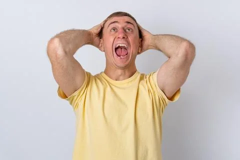 Stressed man screaming with hands on head, experiencing extreme panic and f.. Stock Photos