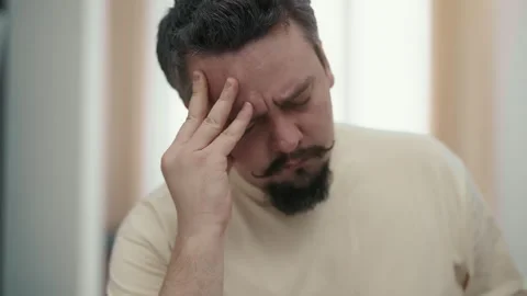 Stressed man suffering from a severe headache Stockbeeldmateriaal 327870852