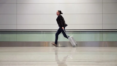 Stressed man with suitcase running late in airport terminal, slowmo Stock Footage 320118824