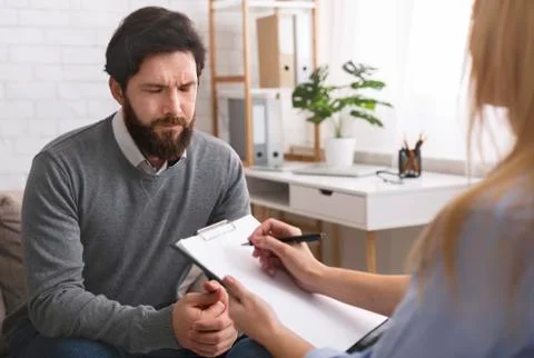 Stressed man talking to psychologist, solving his personal problems 写真素材