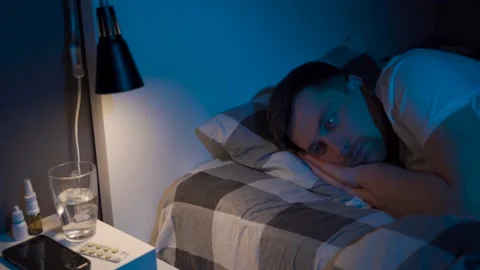Stressed man trying to sleep in bed at night. Young male with open eyes suffers Stock Footage 145439997