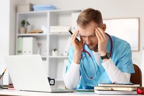 Stressed medical intern studying at table in clinic Stock Photos