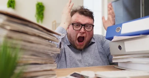 Stressed office worker screaming at paperwork piles amid finance deadline Stock Footage 335543467