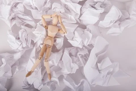 Stressed out jointed manikin doll hands on head laying on crumbled paper Stock Photos
