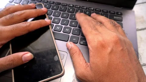 Stressed person using a smartphone and laptop keyboard to work late, concep.. Stock-Footage 345136409