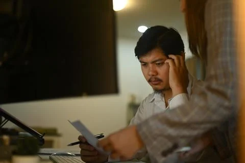 Stressed software developers solving problem, working late at night in their Stock Photos