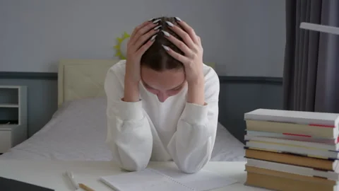 Stressed student holding head in hands with books and laptop on desk Stock Footage 315175013