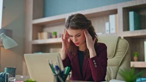 Stressed worker looking computer solving problem. Tired woman rubbing temples Stockfoto's