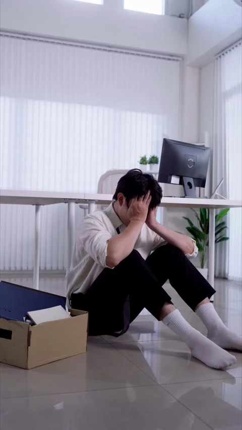 Stressed young Asian man sits on office floor holding head beside resignati.. Stock Footage 345197957