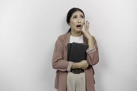 A stressed young Asian student wearing cardigan while holding books, isolat.. Stock-Fotos