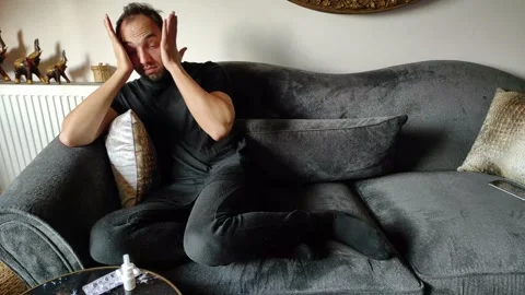 Stressed Young Guy Sitting at Sofa and Having Headache Stock Footage 144080823