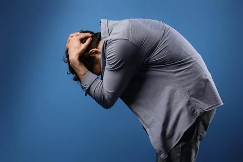 Stressed young man having panic attack on blue background Stock Photos