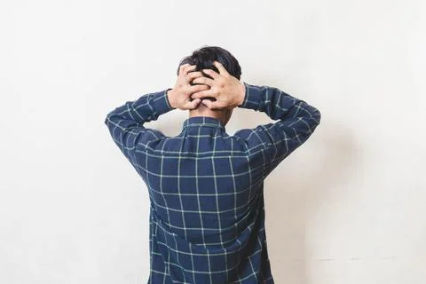 Stressed young man seen from behind holding his head in frustration, expres.. Stock Photos